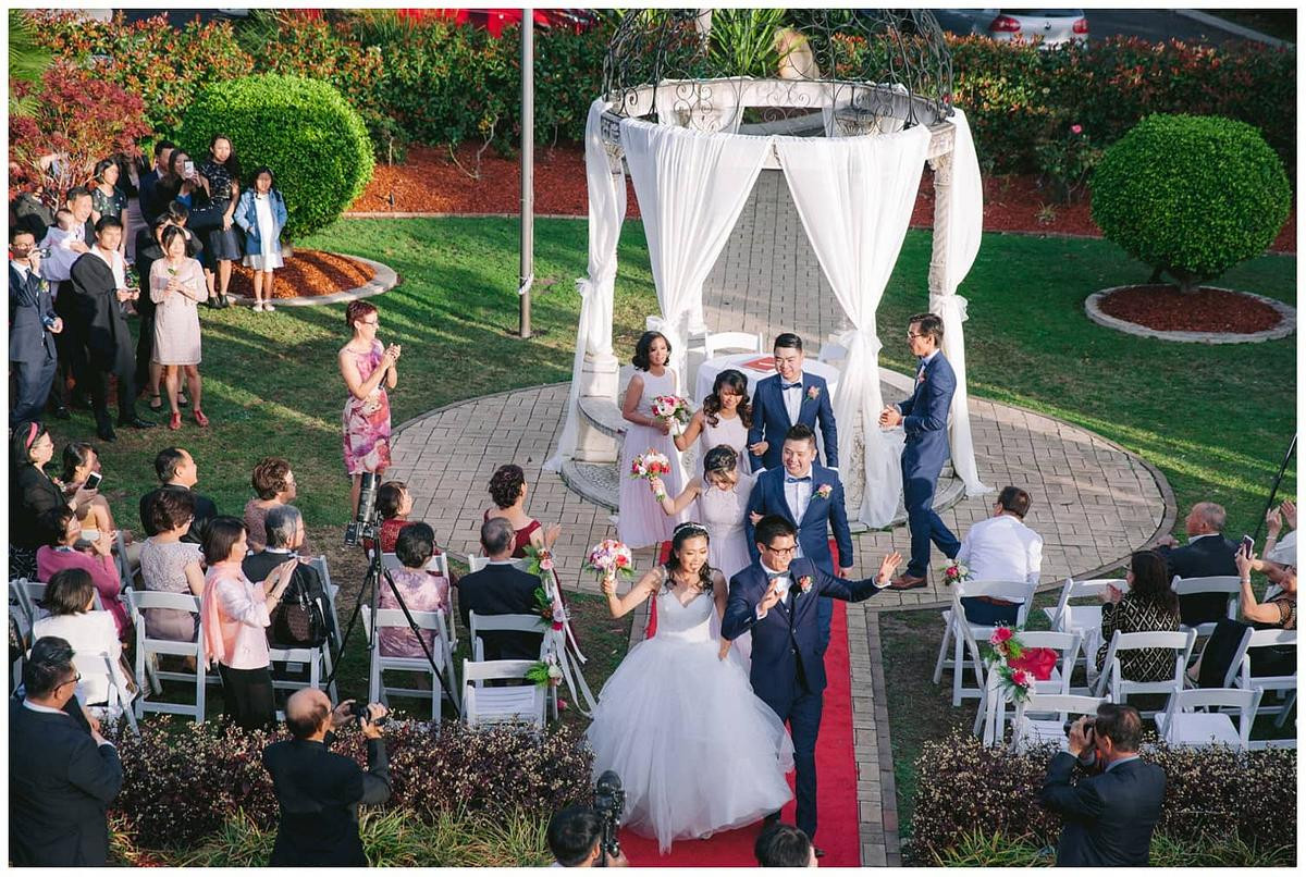 Bride and groom making a joyful wedding recessional, hands raised in celebration at Oatlands House.